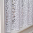 White lace curtain with leaf patterns hanging on a window