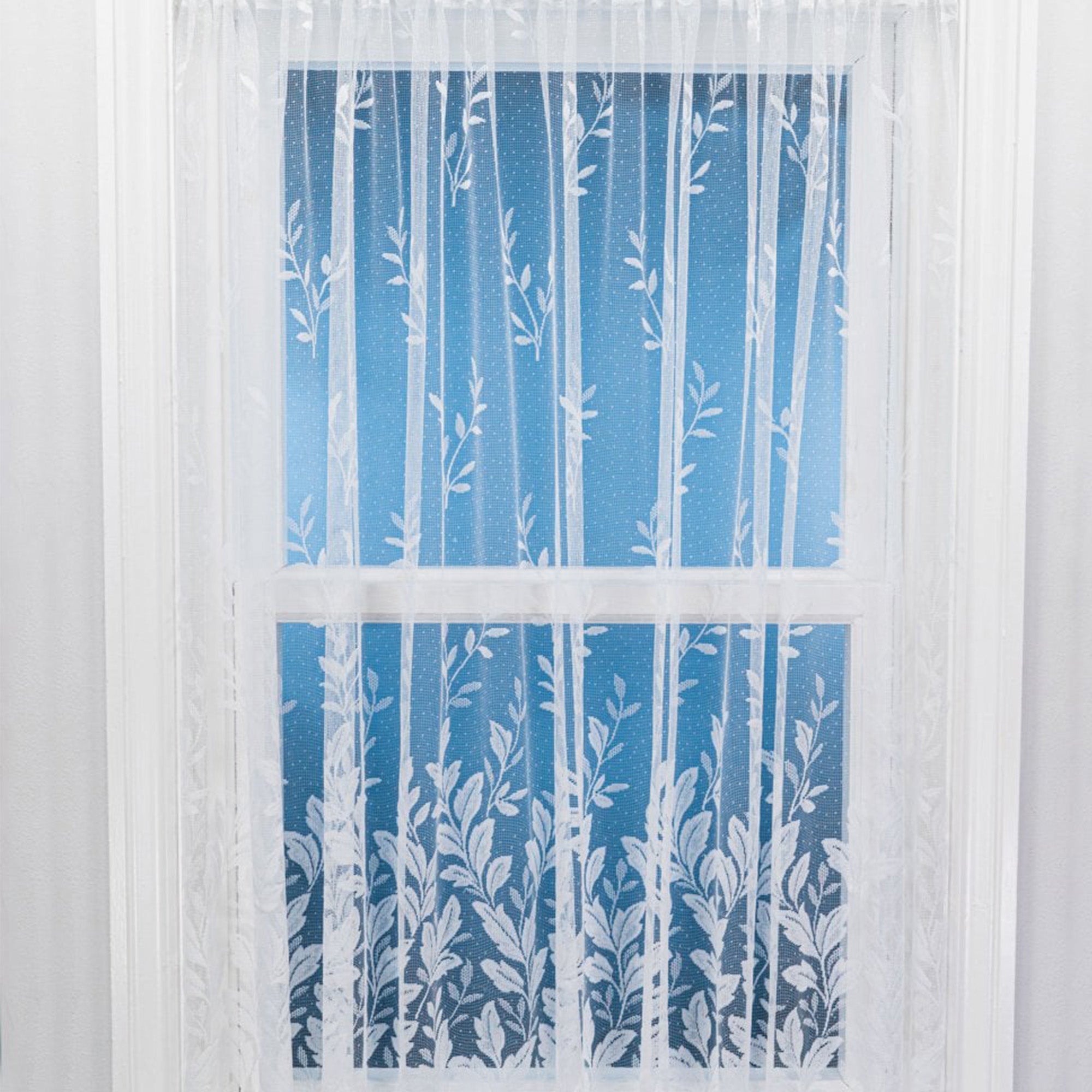 White net curtain with vertical embroidered leaves on a window 