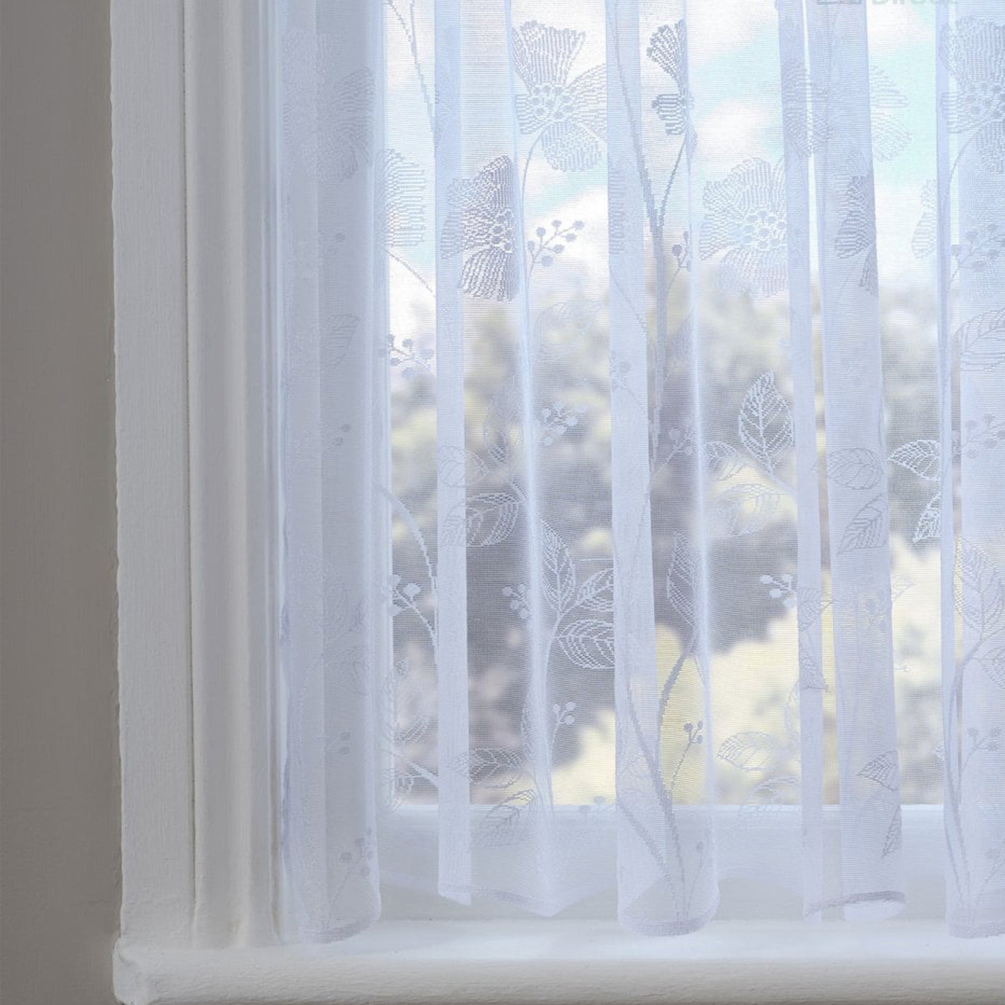 Sheer white curtain with a poppy pattern in front of a window