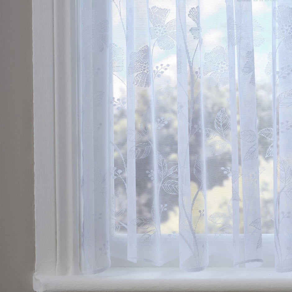 Sheer white curtain with a poppy pattern in front of a window