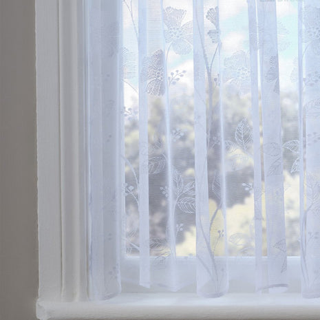 Sheer white curtain with a poppy pattern in front of a window