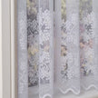 White lace curtains with floral patterns in front of a blurred outdoor background