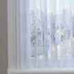 Sheer white lace curtain with floral patterns in a window setting