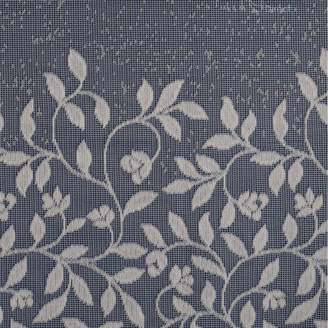 White net curtain fabric with embroidered leaves against a blue background