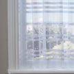 White lace curtains with horizontal sewn stripes against a window 