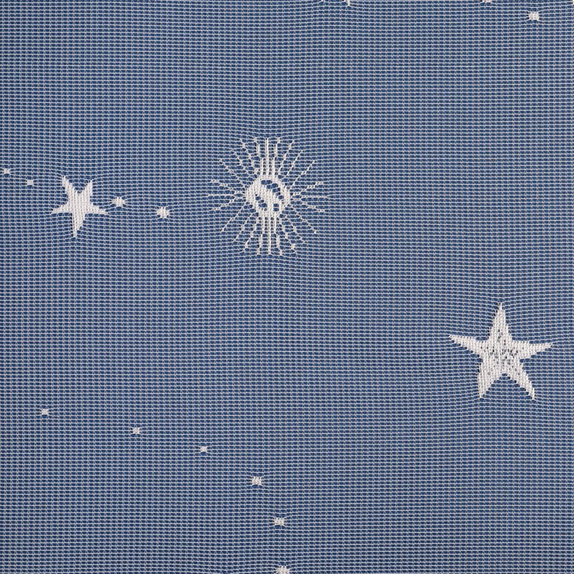 Pattern of stars and moons on lace curtains against a textured blue background