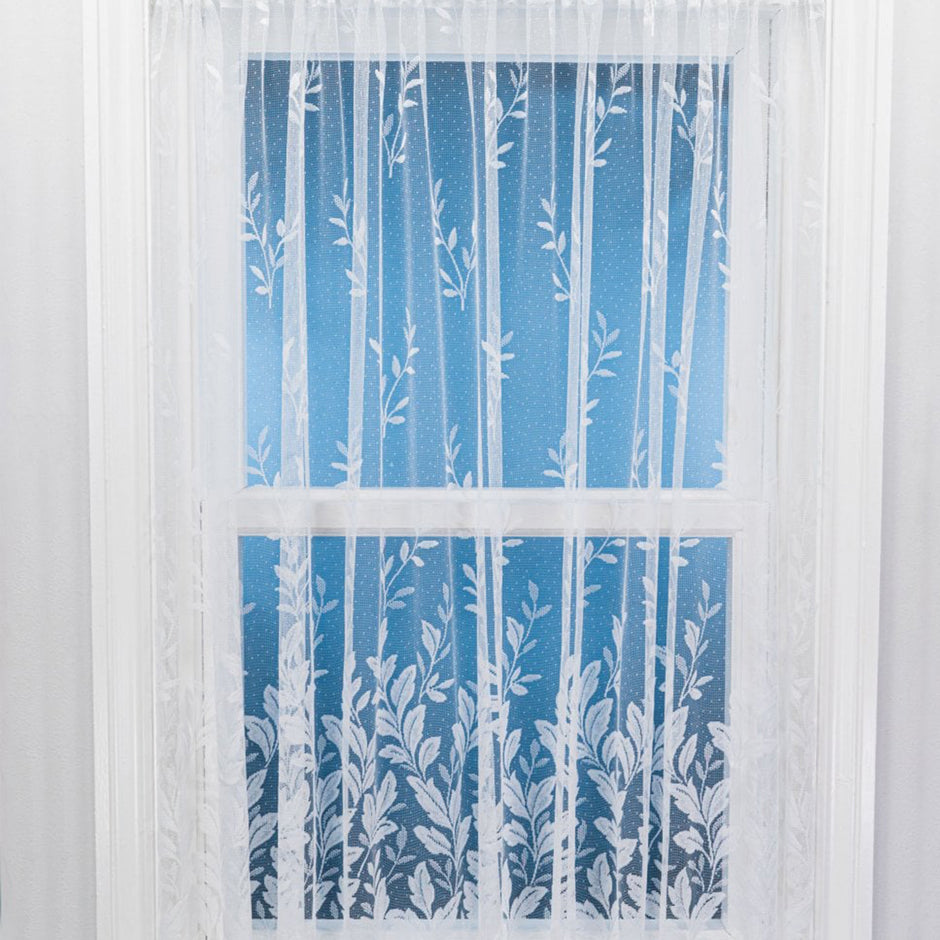 White net curtain with sewn vertical leaves against a window and blue background