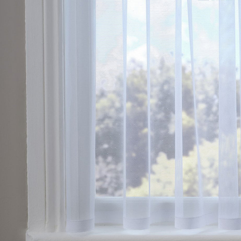 Sheer white curtain with subtle dots against a blurred outdoor view