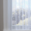 Sheer white curtain with subtle dots against a blurred outdoor view