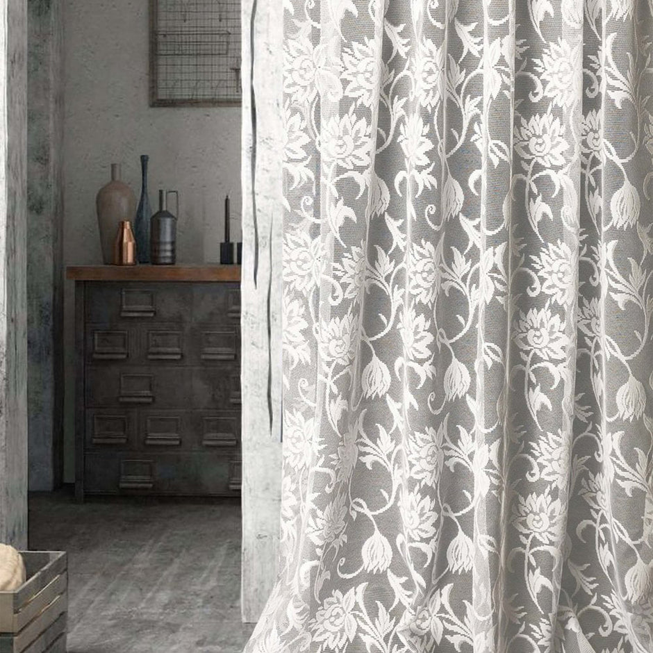 Floral patterned curtain partially covering a room with a wooden cabinet and decorative items.
