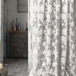 Floral patterned curtain partially covering a room with a wooden cabinet and decorative items.