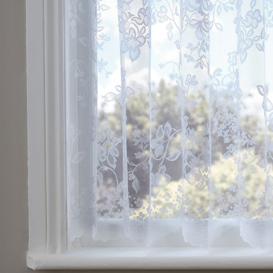 White lace curtain with a flower and leaf pattern in front of a window